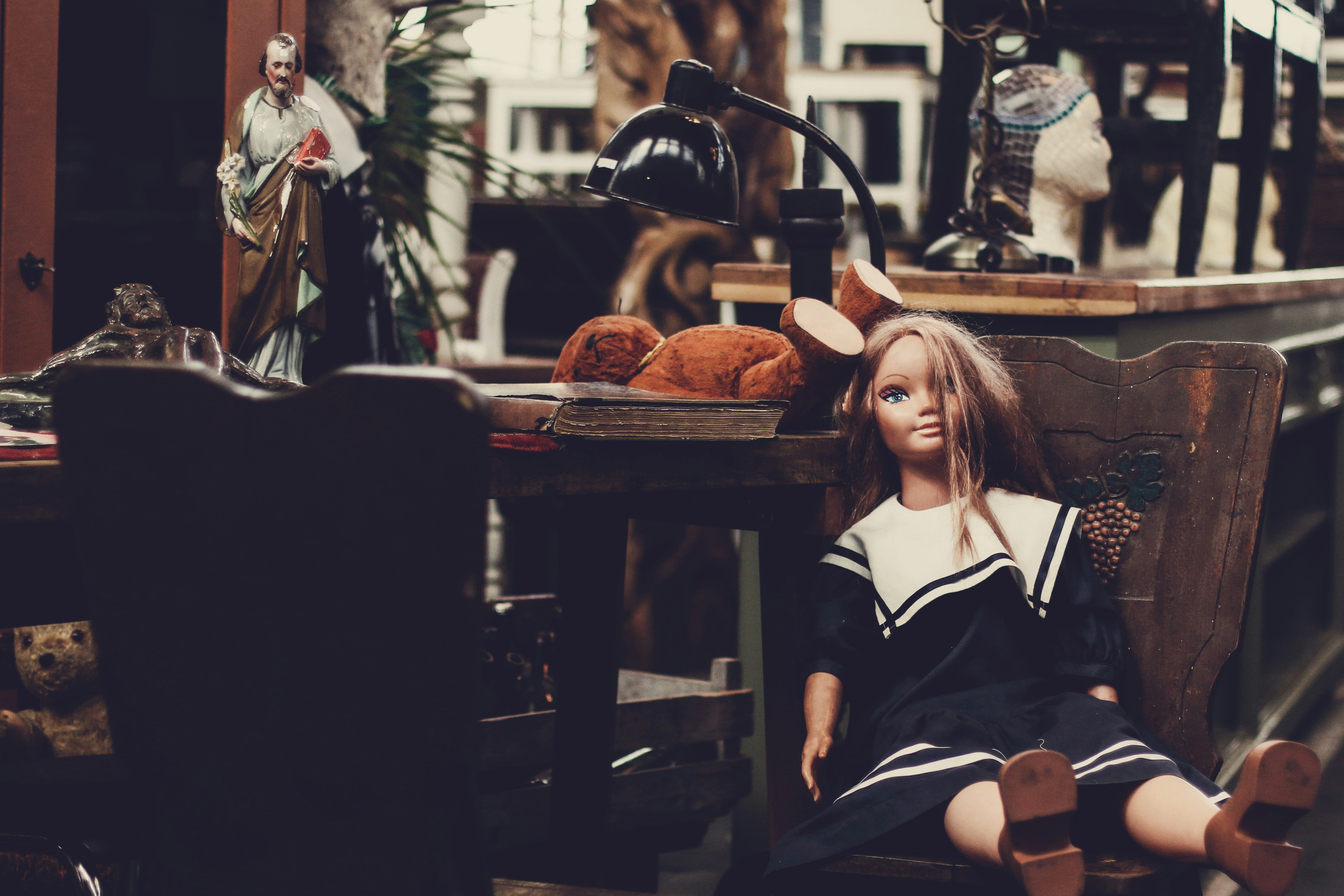 doll sitting on armchair beside desk with desk lamp