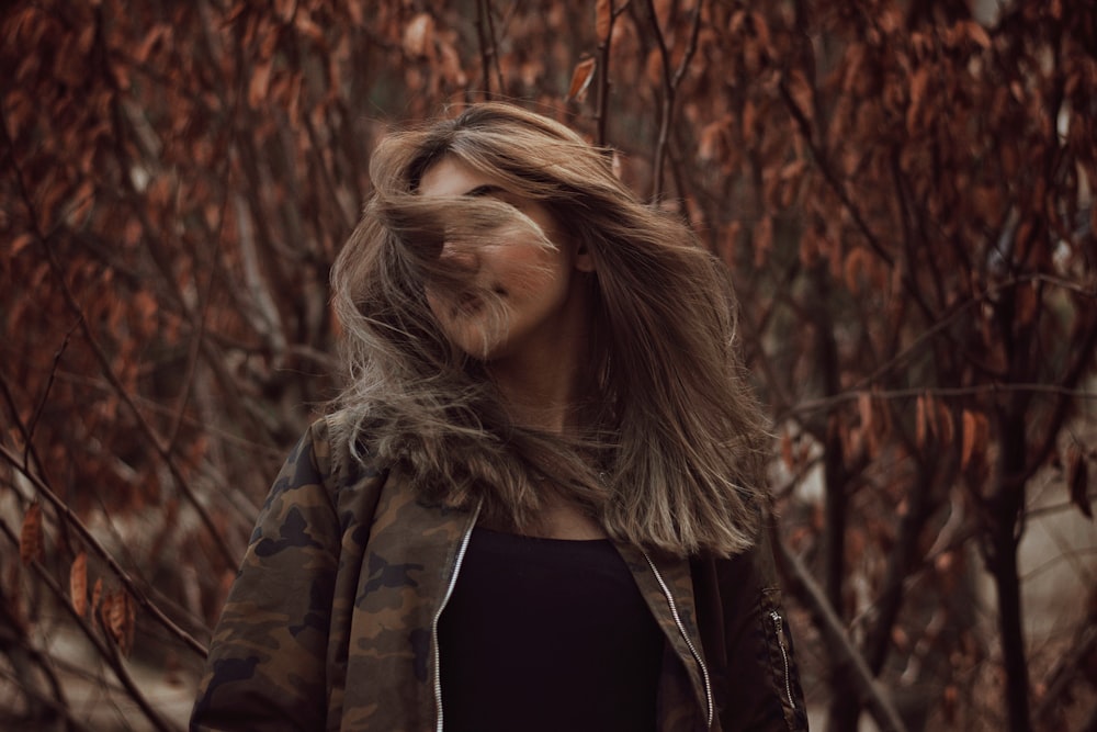 woman in brown and black camouflage jacket whips hair