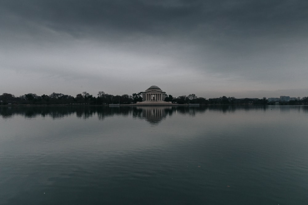 brown concrete building near body of water under cloudy sky