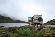 A beautiful landscape featuring a vehicle parked near a lake.