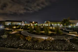 Evening view of a landscaped courtyard illuminated by warm, subtle lighting highlighting sculpted shrubs.