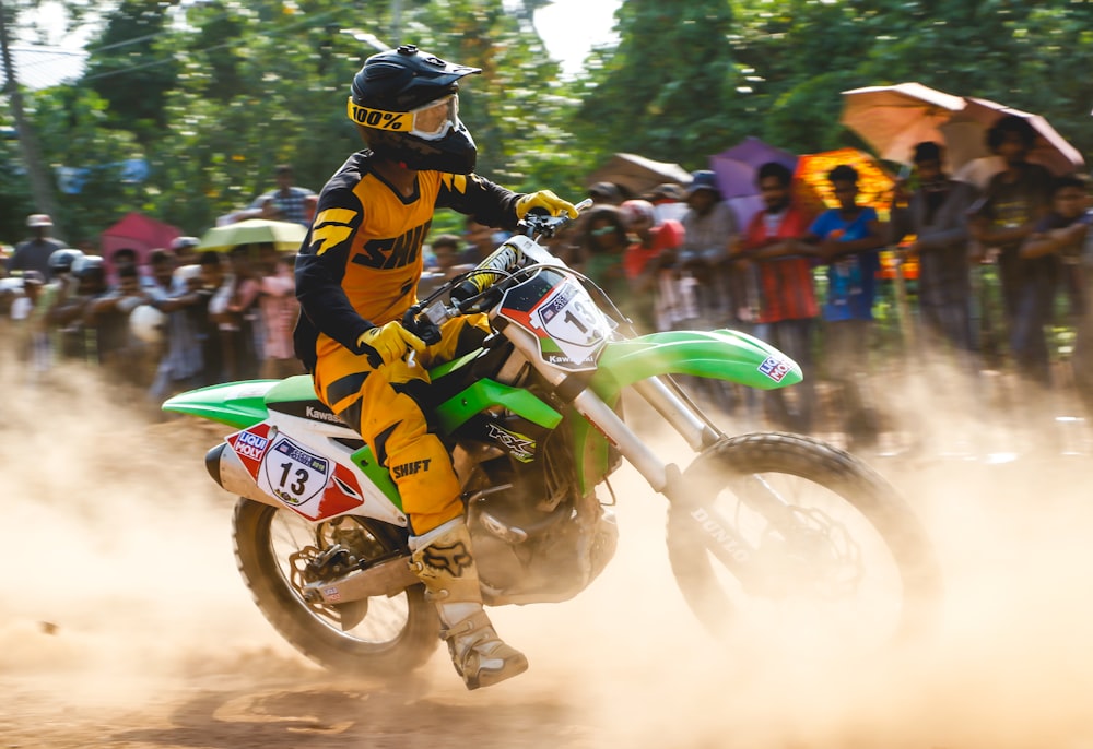 man riding on green dirt bike doing banking