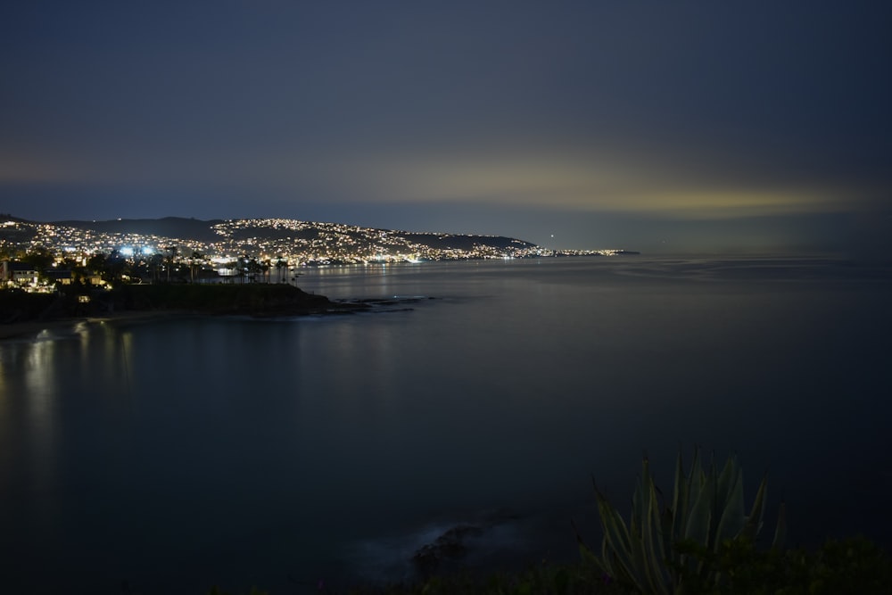 city lights near calm sea during nighttime