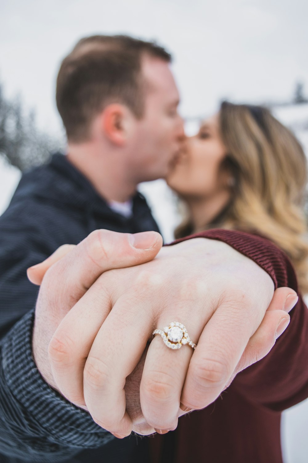 man kissing woman showing her ring