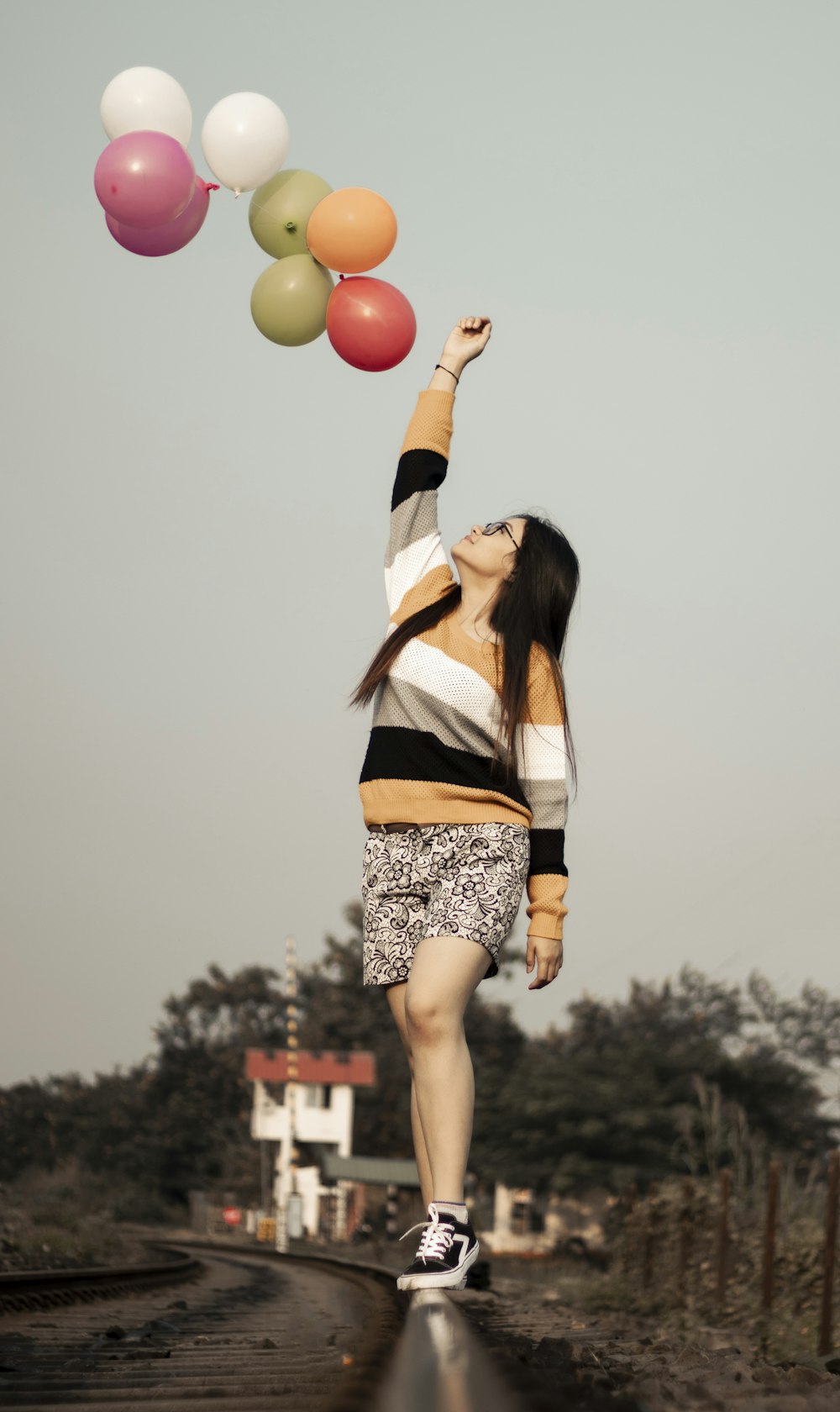 woman on the top of a railway and multicolored balloons