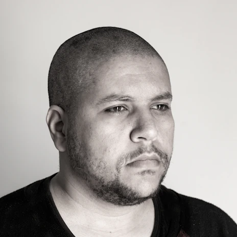 A refined headshot of a man in neutral tones, showcasing subtle lighting and a poised demeanor.