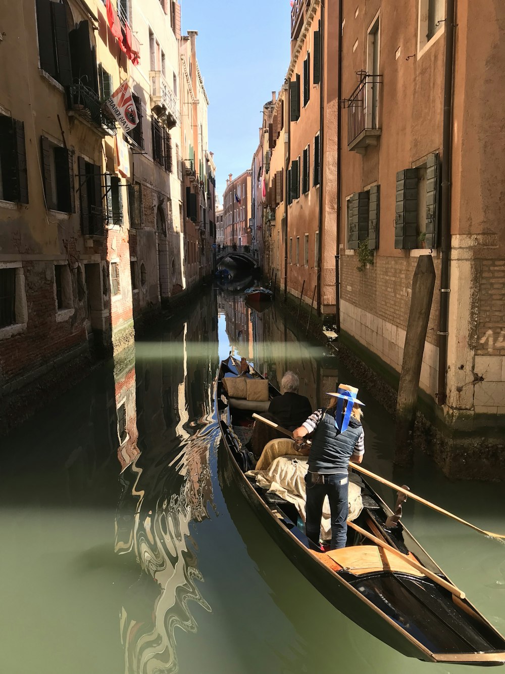 man sailing boat in between buildings during daytime