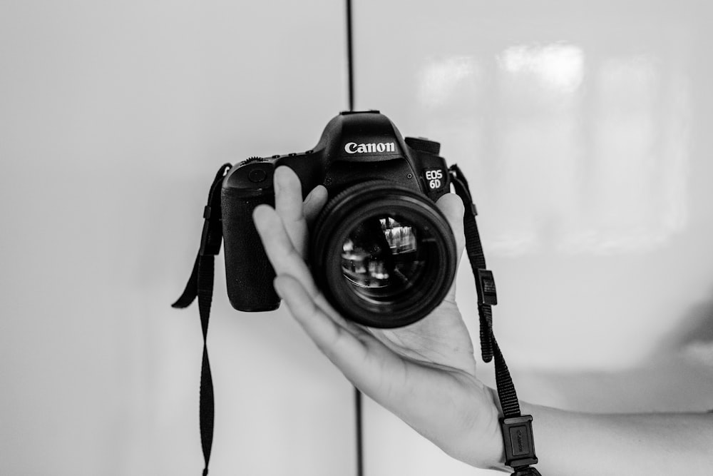 person holding black Canon EOS camera