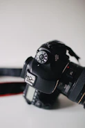 A detailed close-up of a DSLR camera resting on a wooden table beside notes.
