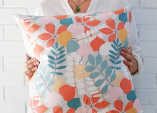 woman holding multicolored floral throw pillow