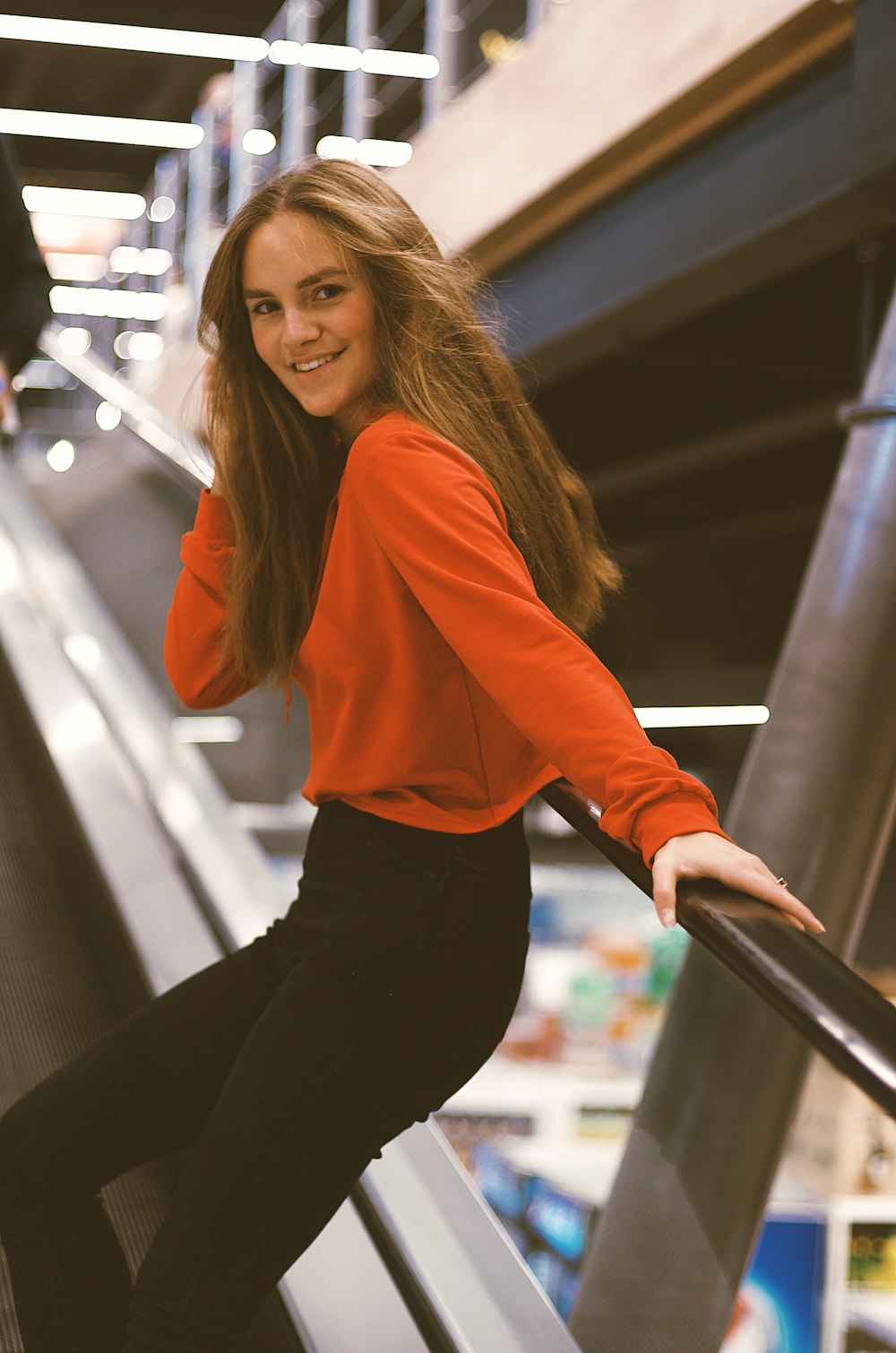 woman leaning on escalator railing while holding her hair