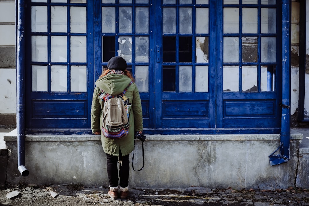 woman facing blue wooden window