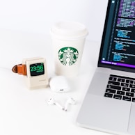 Stacked programming books and a coffee cup next to a sleek laptop setup