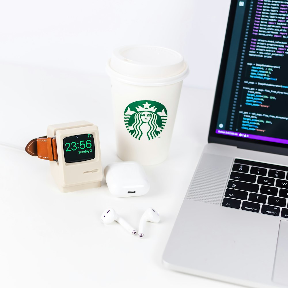 white smartwatch beside Starbucks cup near laptop
