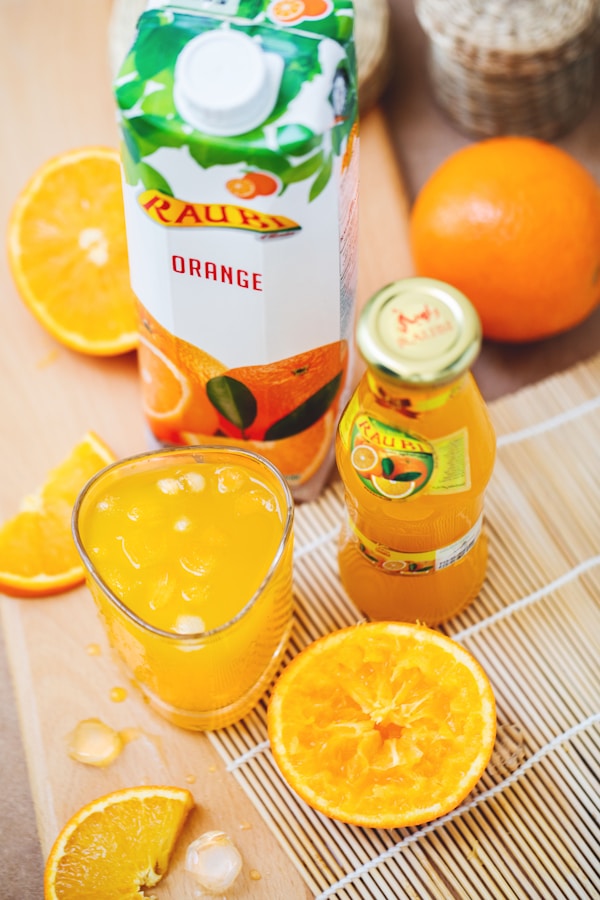 Orange juice in glass beside container