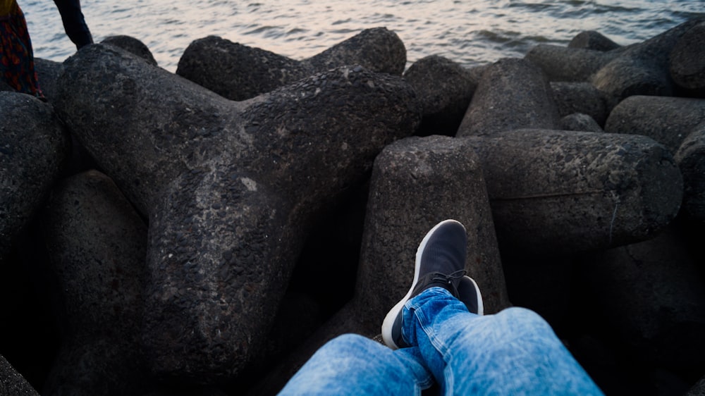 Person in blauen Jeans sitzt vor dem Meer