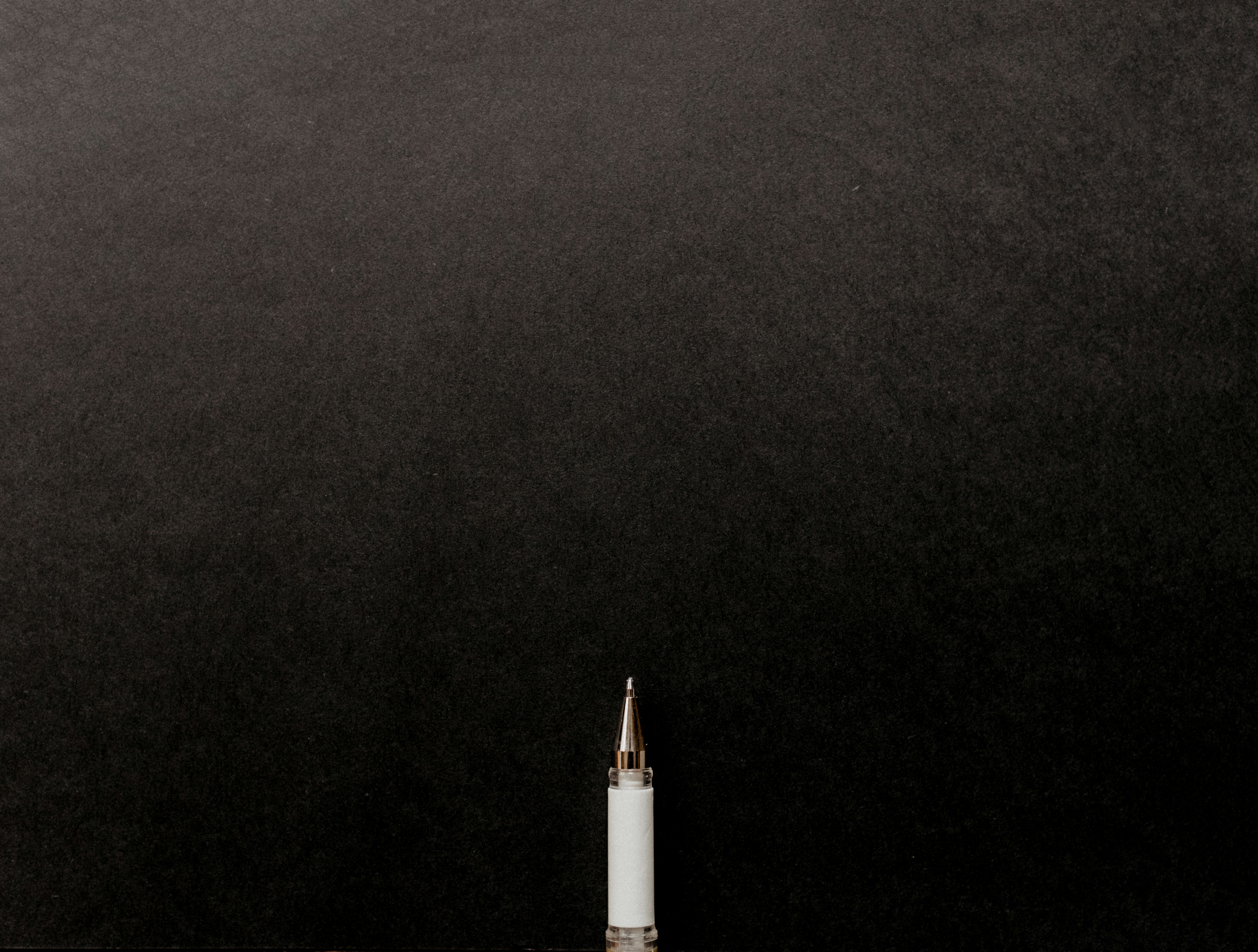 a white tube with a gold tip on a black background