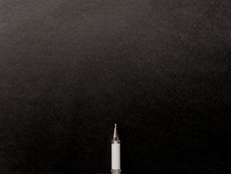 a white tube with a gold tip on a black background