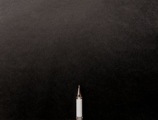 a white tube with a gold tip on a black background