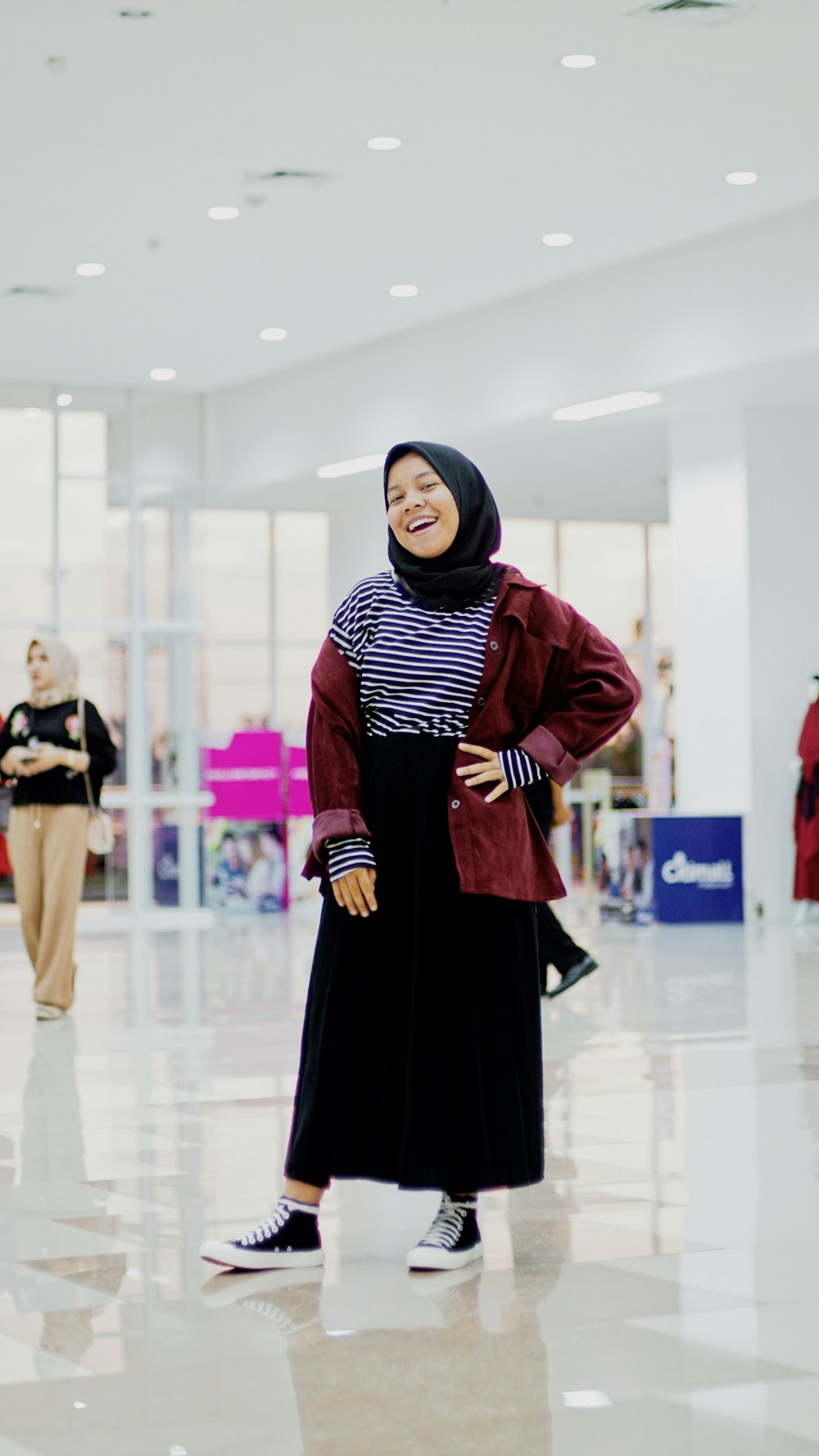 woman wearing black hijab, white-and-black striped shirt, red jacket and black maxi skirt