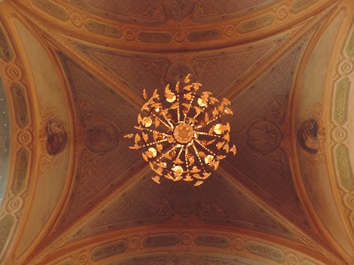 A before-and-after shot showing a high ceiling transformed by a majestic chandelier installation.