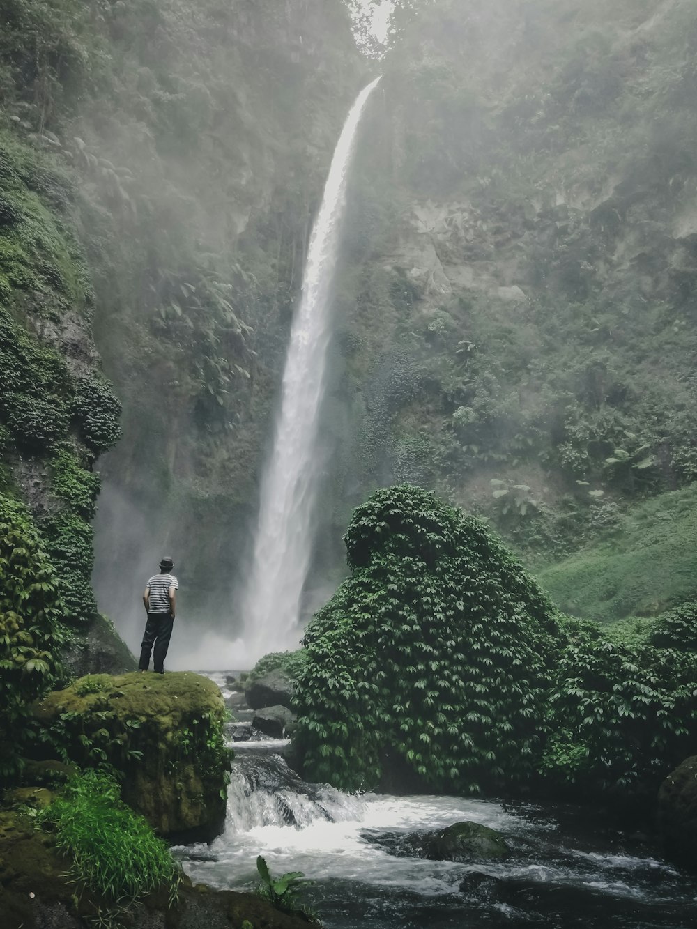 man standing near raging waterfalls