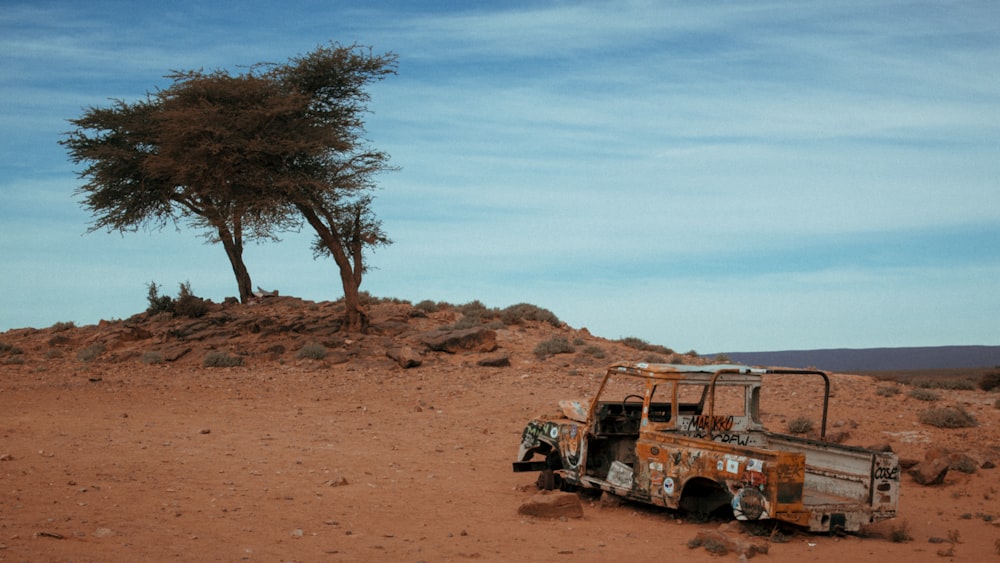 a rusted out truck sitting in the middle of a desert
