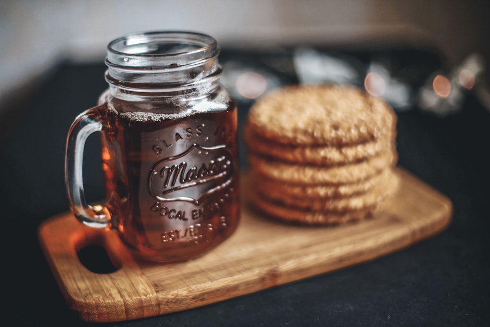 clear glass mason jar beside cookies on brown wooden tray