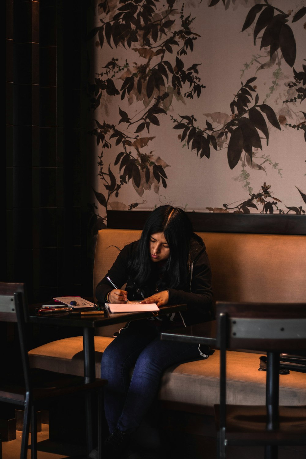 woman writing on white paper while sitting on chair