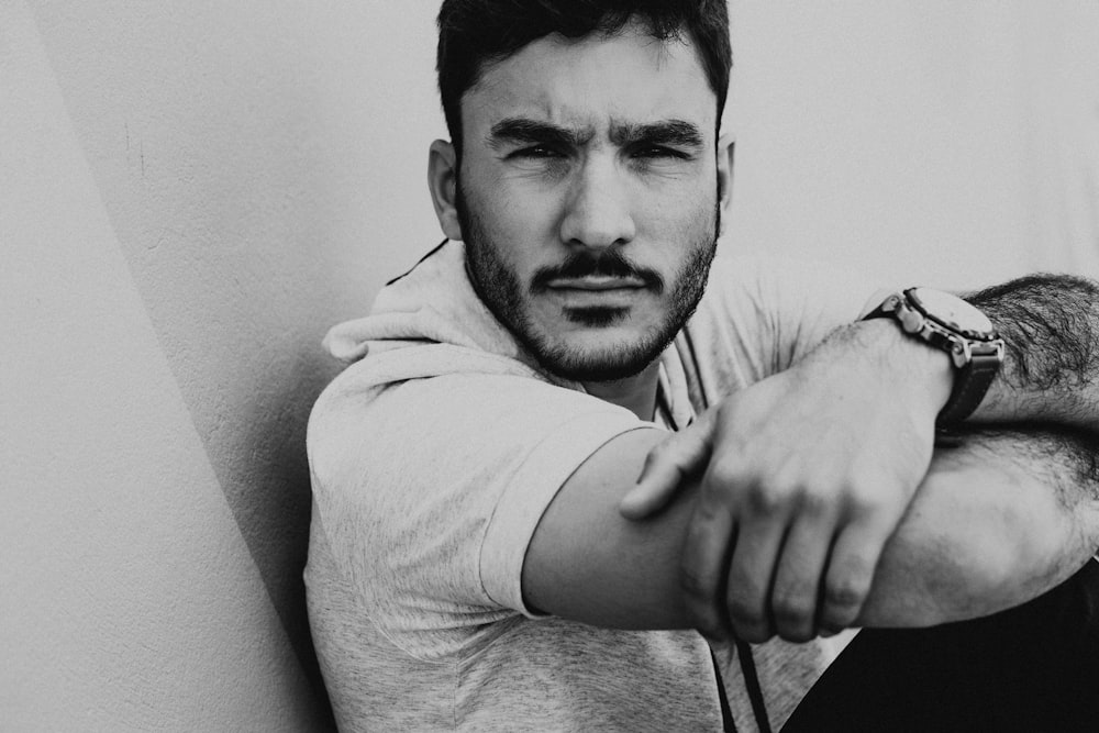 man in white shirt leaning on white painted wall