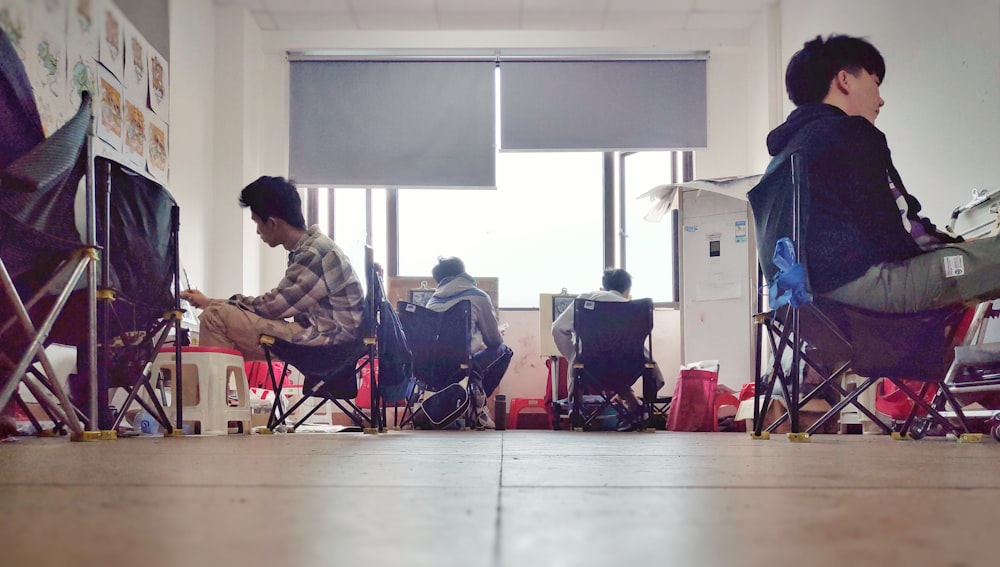 hommes assis sur une chaise à l’intérieur de la pièce