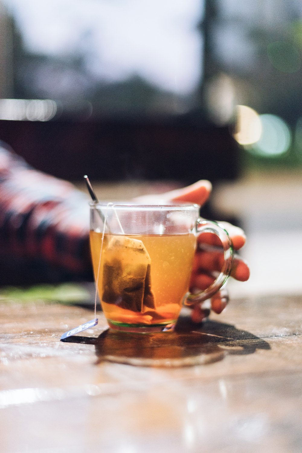 selective focus photography of man reaching for filled glass teacup