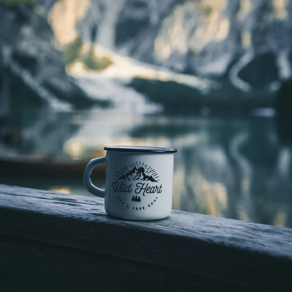 white and black mug on plank