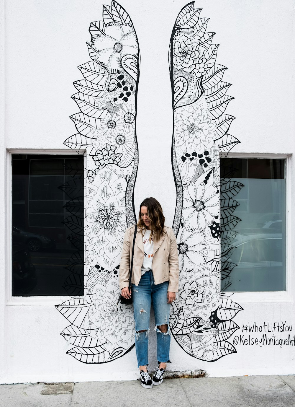 woman standing near wall with wings painting