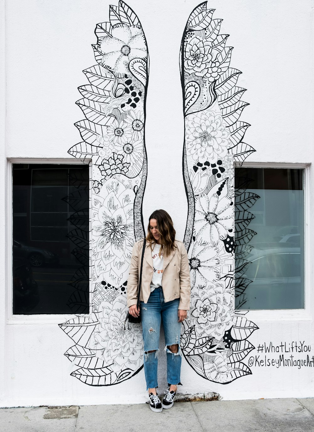 mujer de pie cerca de la pared con alas pintando