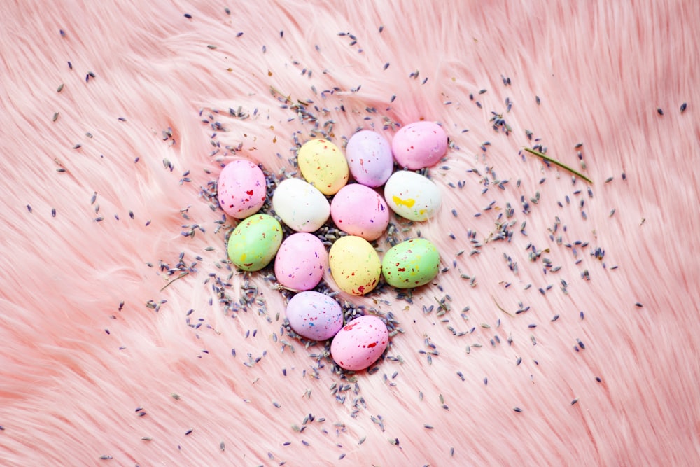 uma pilha de ovos coloridos sentados em cima de uma pele rosa