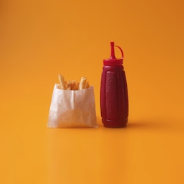 A vibrant photo of a ketchup bottle pouring rich, glossy ketchup onto a plate of crispy fries.