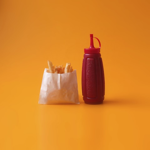 A vibrant photo of a ketchup bottle pouring rich, glossy ketchup onto a plate of crispy fries.