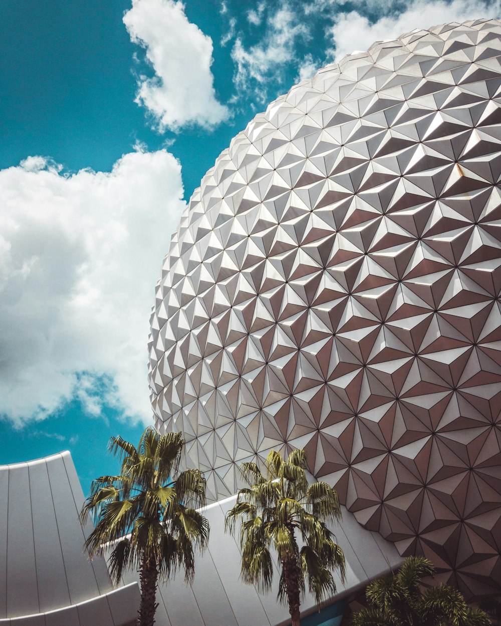 a building with a dome and palm trees in front of it