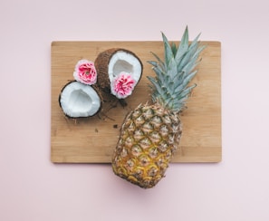 pineapple fruit beside coconut on top of chopping board