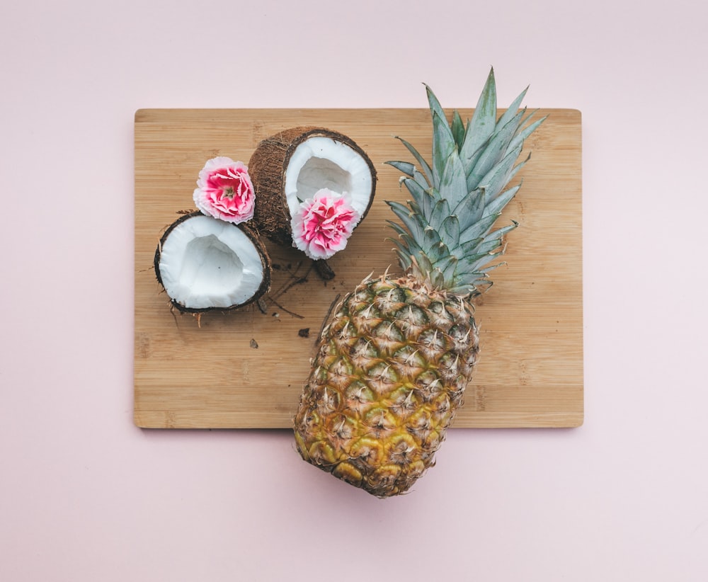 fruta de piña junto al coco encima de la tabla de cortar