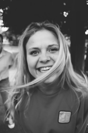 A torn photograph of a smiling woman with a dark, blurred background.