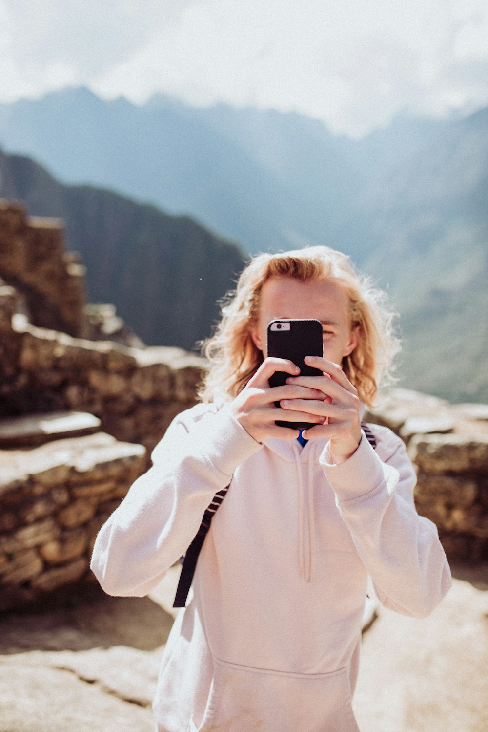 Frau trägt weißen Pullover und macht Selfie