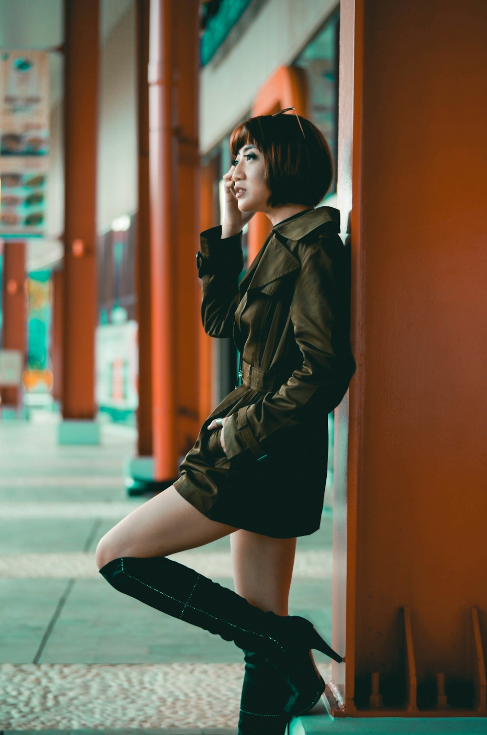 shallow focus photo of woman leaning on brown wall