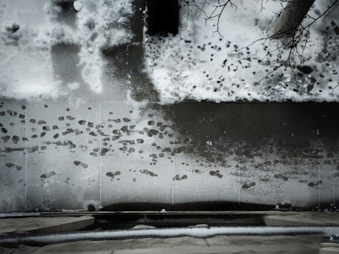 A salted sidewalk free of snow with footprints visible.