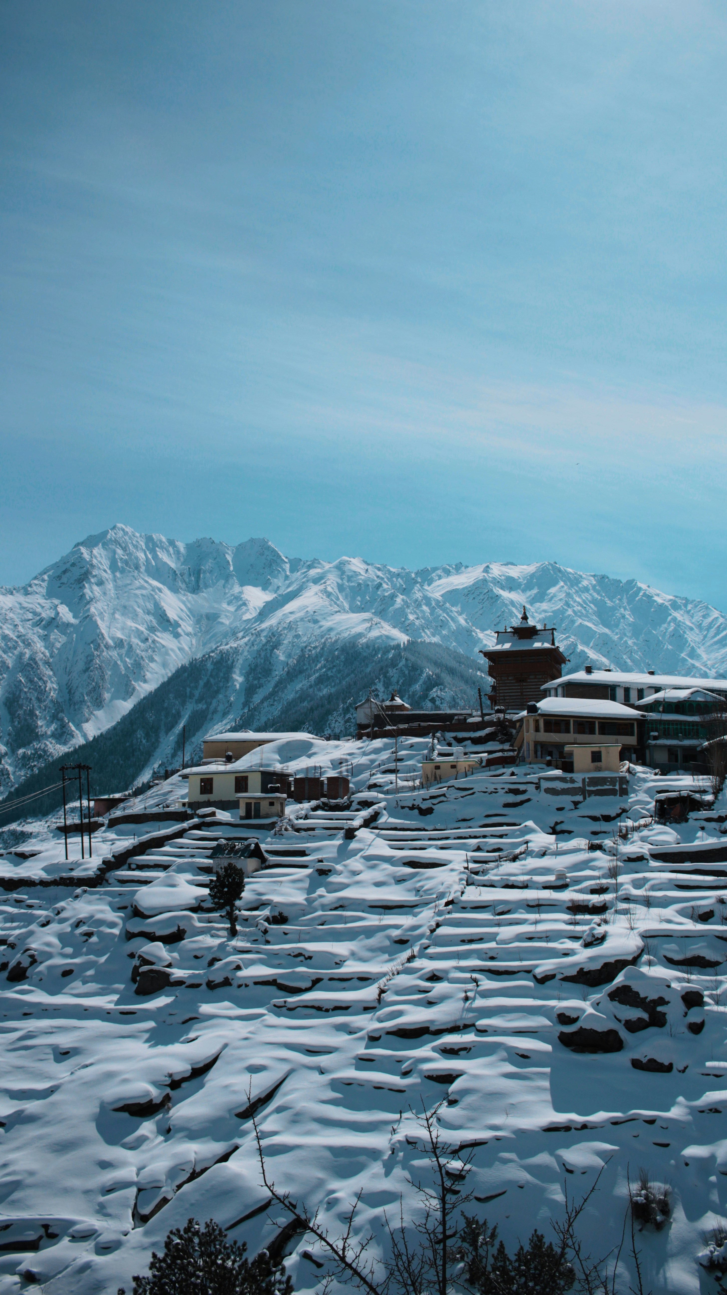 Fotografía aérea de un pueblo cubierto de nieve en la cima de la colina durante el día
