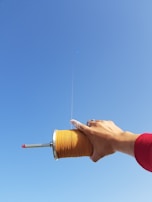 Hands holding a spool of kite string ready to launch a kite into the breeze