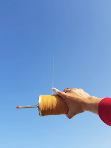 Close-up of hands tying strong kite strings with vibrant spools in the background.