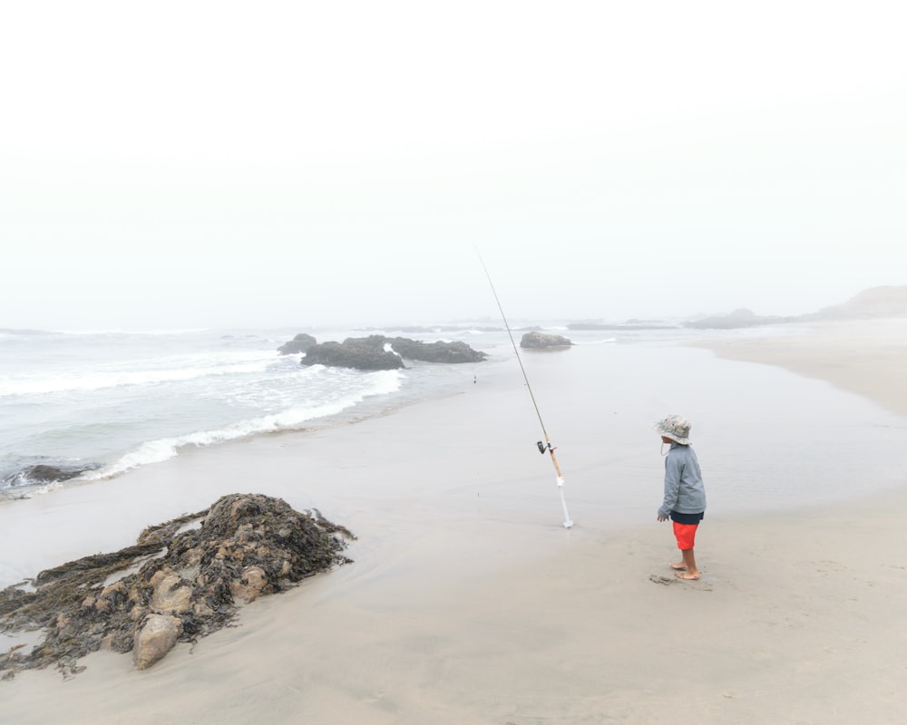 standing boy near seashore under cloudy sky