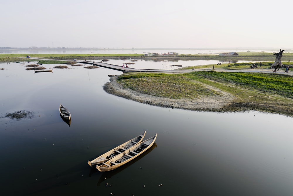 three brown canoe boats on body of water during daytime